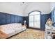 Comfortable living room featuring navy blue wood-paneled walls, arched window with plantation shutters, and patterned rug at 11772 Sugar Hill Rd, Davidson, NC 28036