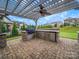 Outdoor kitchen under a pergola, featuring stone counters, a grill, and a mini-fridge, perfect for entertaining guests at 1190 Arges River Dr, Fort Mill, SC 29715