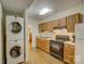 Kitchenette featuring stackable washer and dryer, wood cabinets, and essential appliances in a compact space at 12125 Mountainside Ln, Charlotte, NC 28278