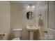 Powder room with pedestal sink, elongated toilet, and modern lighting fixtures on tile-look floors at 12125 Mountainside Ln, Charlotte, NC 28278