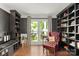 Stylish library with dark bookcases, a red leather chair, and natural light from the windows at 12602 Angel Oak Dr, Huntersville, NC 28078