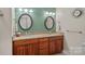 Bathroom featuring double sinks with a granite countertop and custom wood cabinets, combining elegance and functionality at 166 Pinnacle Shores Dr, Mooresville, NC 28117