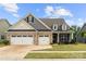 Charming two-story home featuring a brick facade, two-car garage, and a welcoming front porch at 17028 River Race Dr, Huntersville, NC 28078