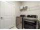 Laundry room with modern washer and dryer, storage shelf, and tile floor at 17028 River Race Dr, Huntersville, NC 28078