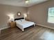 Bright bedroom with wood-look flooring, a ceiling fan, and a decorative mirror at 190 Watering Trough Rd, Statesville, NC 28677