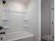 White bathtub and shower combo with shelving and black fixtures offers a clean and modern bathing experience at 1941 32Nd Ne St, Hickory, NC 28601