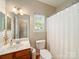 Well-lit bathroom with a wooden vanity, white sink, and a shower with a curtain, offering a clean and functional space at 2111 Elendil Ln, Charlotte, NC 28269