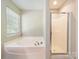 Bright bathroom featuring a large tub, a shower, a window and neutral decor at 2111 Elendil Ln, Charlotte, NC 28269