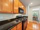 Well-lit kitchen featuring wood cabinets, black countertops, and stainless steel appliances at 2111 Elendil Ln, Charlotte, NC 28269