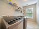 Functional laundry room with modern washer and dryer, shelving for storage, and a window for natural light, making chores easier at 2111 Elendil Ln, Charlotte, NC 28269