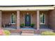 Inviting brick front porch with black front door, columns, potted plants, and ambient lighting at 2458 Genelia Dr, Claremont, NC 28610