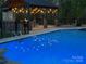 An illuminated pool at night with a patio and fireplace in the background at 2458 Genelia Dr, Claremont, NC 28610