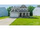 Charming two-story home with a manicured lawn, neutral siding, stone accents, and a welcoming front porch at 2714 Woodlands Creek Dr, Monroe, NC 28110