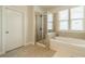 A well-lit bathroom features a separate tub and shower, tiled floors, and a bright window at 2714 Woodlands Creek Dr, Monroe, NC 28110