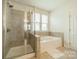A well-lit bathroom features a separate tub and shower, tiled floors, and a bright window at 2714 Woodlands Creek Dr, Monroe, NC 28110