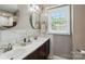Bright bathroom with double sinks, white countertops, wood cabinets, and a large window at 314 Sunnywood Ln, Charlotte, NC 28270