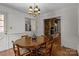 Traditional dining room featuring hardwood floors, an ornate chandelier, and access to a brick fireplace at 3209 Sedgefield Rd, Statesville, NC 28625