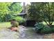View of backyard with mature trees and landscaping, including hydrangeas, leading to a basement garage at 344 Lucas Rd, Star, NC 27356