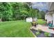 Expansive backyard featuring a lush lawn, storage sheds, and a charming patio seating area at 5748 Timbertop Ln, Charlotte, NC 28215