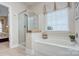 A relaxing bathroom featuring a glass shower, separate tub, and large window at 5748 Timbertop Ln, Charlotte, NC 28215