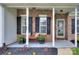 Inviting front porch with brick detail, white columns, and cozy bench seating with colorful pillows at 5748 Timbertop Ln, Charlotte, NC 28215