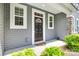 Inviting front porch with a black front door, gray siding, stone accents, and green bushes at 5836 Clan Maclaine Dr, Charlotte, NC 28278