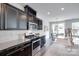 Well-equipped kitchen featuring stainless steel appliances, granite countertops, dark cabinets, and view of dining area at 5836 Clan Maclaine Dr, Charlotte, NC 28278