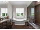 Spa-like bathroom featuring a soaking tub, walk-in shower, tile floors, and large window with backyard views at 5915 Vidal Ln, Charlotte, NC 28226