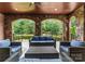 Charming covered outdoor patio featuring stone arches, wood ceilings, elegant seating, and beautiful backyard views at 5915 Vidal Ln, Charlotte, NC 28226
