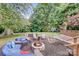 Inviting backyard with a stone fire pit, cozy seating, hammock, and lush green surroundings at 592 Woodcrest Dr, Gastonia, NC 28056