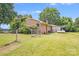 Back exterior of a brick home with a fenced yard, propane tank, and mature trees creating a serene and private outdoor space at 6300 Mount Pleasant S Rd, Concord, NC 28025