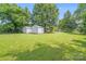 Spacious backyard with green grass, bordered by mature trees, and featuring two storage sheds at 6300 Mount Pleasant S Rd, Concord, NC 28025