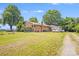 View of a brick house with a well-maintained lawn, showing covered parking and mature trees at 6300 Mount Pleasant S Rd, Concord, NC 28025