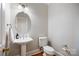 Half bathroom with pedestal sink, round mirror, and hardwood floors at 6409 Barkley Farm Rd, Huntersville, NC 28078
