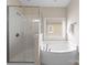 Bright bathroom featuring glass shower, soaking tub, and tile flooring at 8830 Artesa Mill Ln, Charlotte, NC 28214