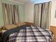 Comfortable bedroom with a gray plaid comforter, striped curtains, and wood paneling, offering a peaceful retreat at 102 Papoose Ct # D117, Mount Gilead, NC 27306