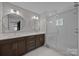 Modern bathroom featuring dual sinks, sleek vanity, and glass-enclosed shower with white subway tile at 1207 Lakedell Dr, Charlotte, NC 28215