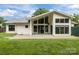 Rear exterior view of the home showcasing a large lawn and covered patio with expansive windows at 1207 Lakedell Dr, Charlotte, NC 28215