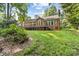 A brick home boasts a large deck and lawn, framed by mature trees, for a peaceful backyard setting at 122 Waterford Dr, Mooresville, NC 28117