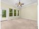 Light-filled bedroom featuring a ceiling fan, tray ceilings, plush carpeting, and windows with backyard views at 122 Waterford Dr, Mooresville, NC 28117