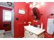 Bathroom featuring a red wall, white fixtures, vanity sink, oval mirror and decorative accessories at 1371 Hawks Nest Rd, York, SC 29745