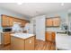 Well-lit kitchen with an island, wooden cabinets, white appliances, and hardwood floors at 152 Hampshire Dr, Mooresville, NC 28115
