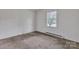 Bedroom featuring a window, neutral carpet, and baseboard heating at 1613 Hamilton St, Charlotte, NC 28206