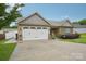 Charming home boasts a two-car garage, stone accents, manicured lawn, and inviting facade at 2021 Chantilly Ln, Salisbury, NC 28146