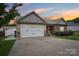 Charming home boasts a two-car garage, stone accents, manicured lawn, and inviting facade at dusk at 2021 Chantilly Ln, Salisbury, NC 28146