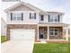Charming two-story home featuring stone accents, blue shutters, a two-car garage, and a well-maintained lawn at 221 Paige Rd, Kings Mountain, NC 28086
