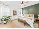 Inviting bedroom with green accent wall, hardwood floors, a cozy bench, and natural light from the window at 3110 Streamside Dr, Davidson, NC 28036