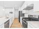 Modern kitchen featuring stainless steel appliances, white cabinets, quartz countertops, and stylish hardwood flooring at 3110 Streamside Dr, Davidson, NC 28036