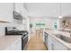 Open-concept kitchen with white cabinets, quartz countertops, stainless steel appliances, and a view into the dining area at 3110 Streamside Dr, Davidson, NC 28036