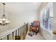 Hallway landing area with chair next to window, crown molding, and black metal railing at 3128 Ethereal Ln, Charlotte, NC 28226